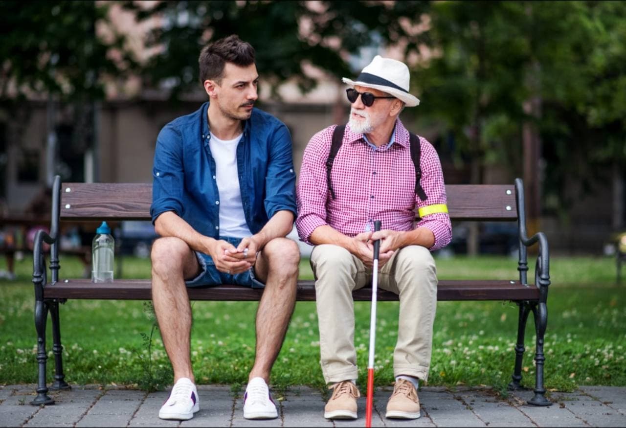 Junger Mann im Gespräch mit älterem Mann auf Parkbank — Hoffnung teilen